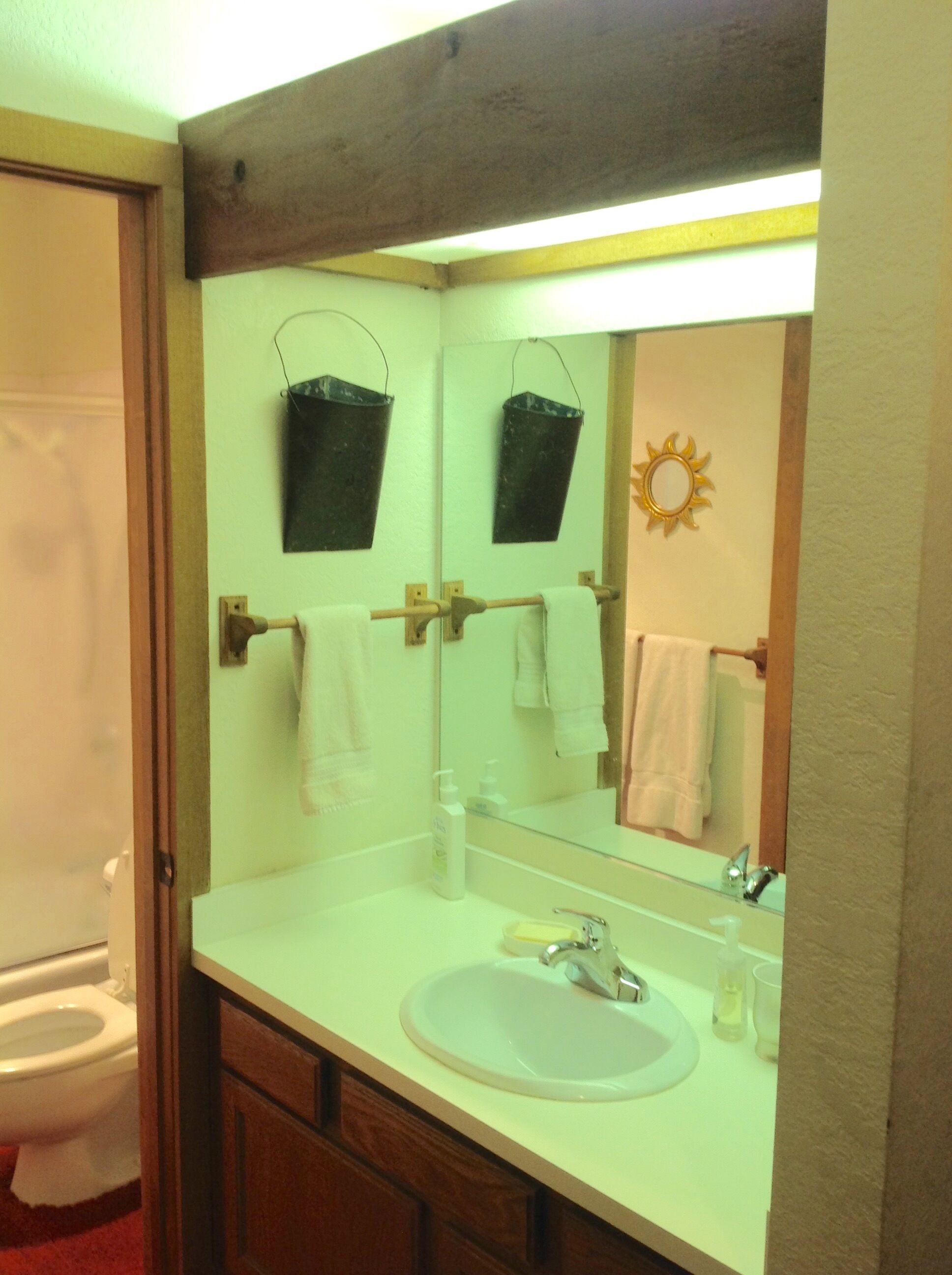A bathroom with a white sink, a mirror, and two hanging black buckets.