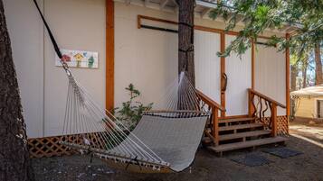 Relax in a serene outdoor space with a hammock suspended between trees and a covered porch.