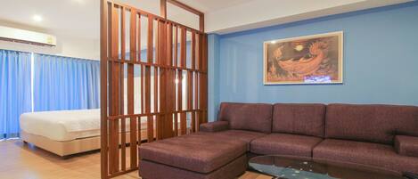 Un salón con sofá, reposapiés y una mesa de centro de vidrio.