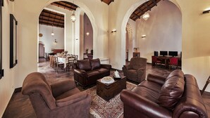 A spacious living area with leather sofas, a coffee table, and a dining area with a table set for a meal. - Resort Borgo La Fasana formula (RG)
