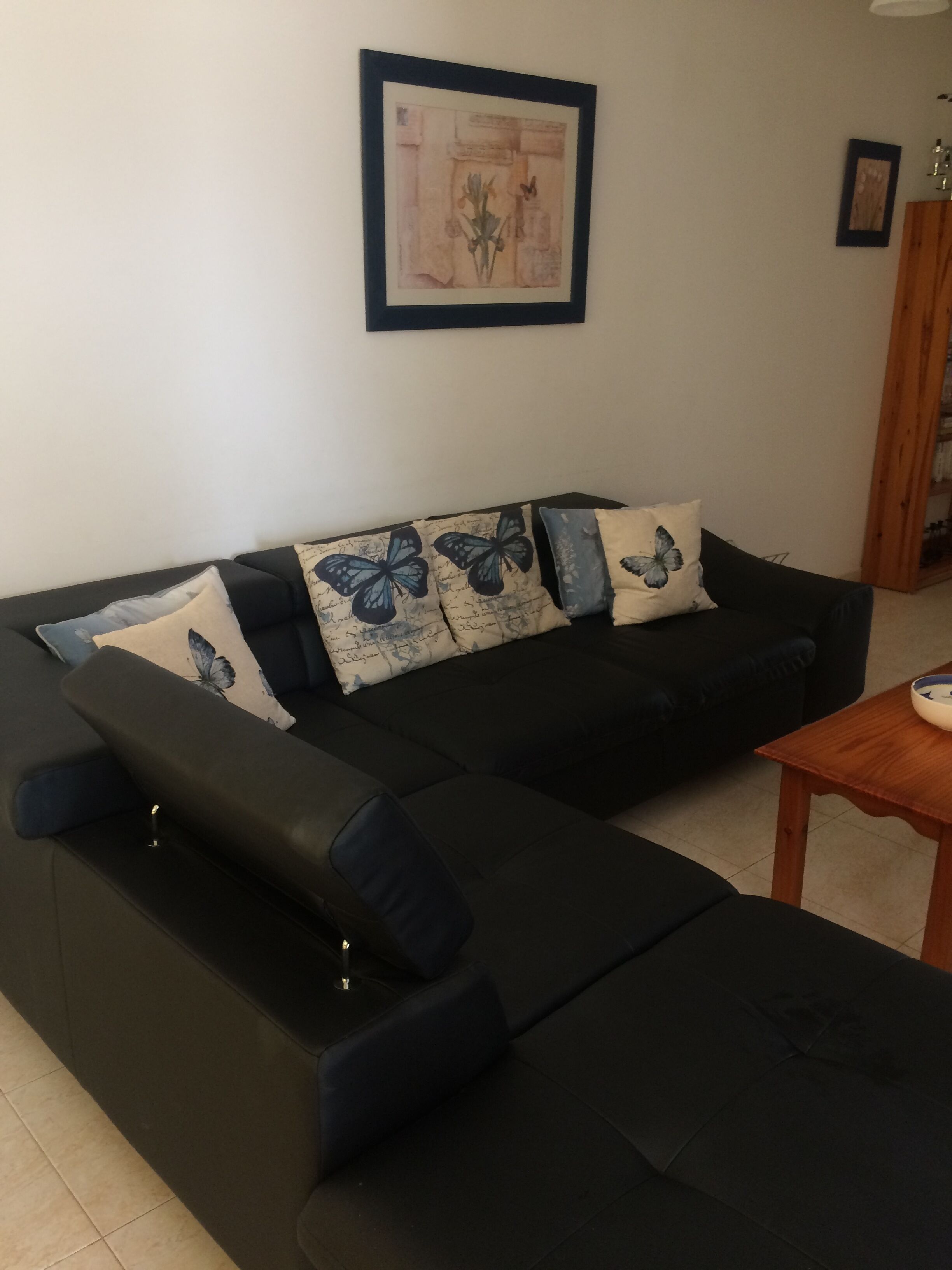 A modern living room with a sectional sofa, a wooden coffee table, and a framed artwork on the wall.