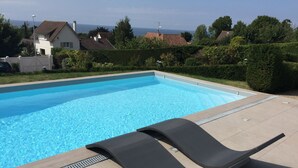 Una piscina con acqua cristallina e un bordo piastrellato. Due sdraio si trovano sulla terrazza.