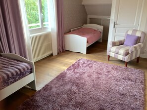 A bedroom with a bed, a chair, a window, and a radiator.