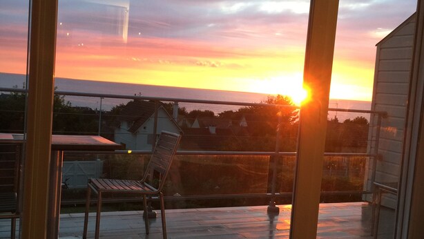 Un balcone con vista sul tramonto, una sedia e un tavolo.
