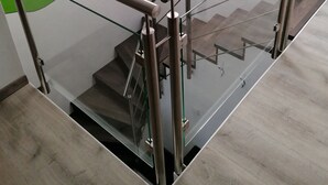 Un escalier moderne avec des rampes en verre et un mur d’accent de couleur verte.