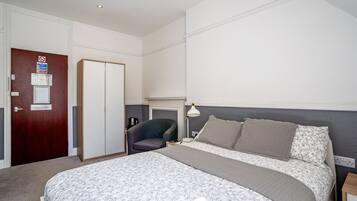 A bedroom with a bed, a chair, a desk, and a door.