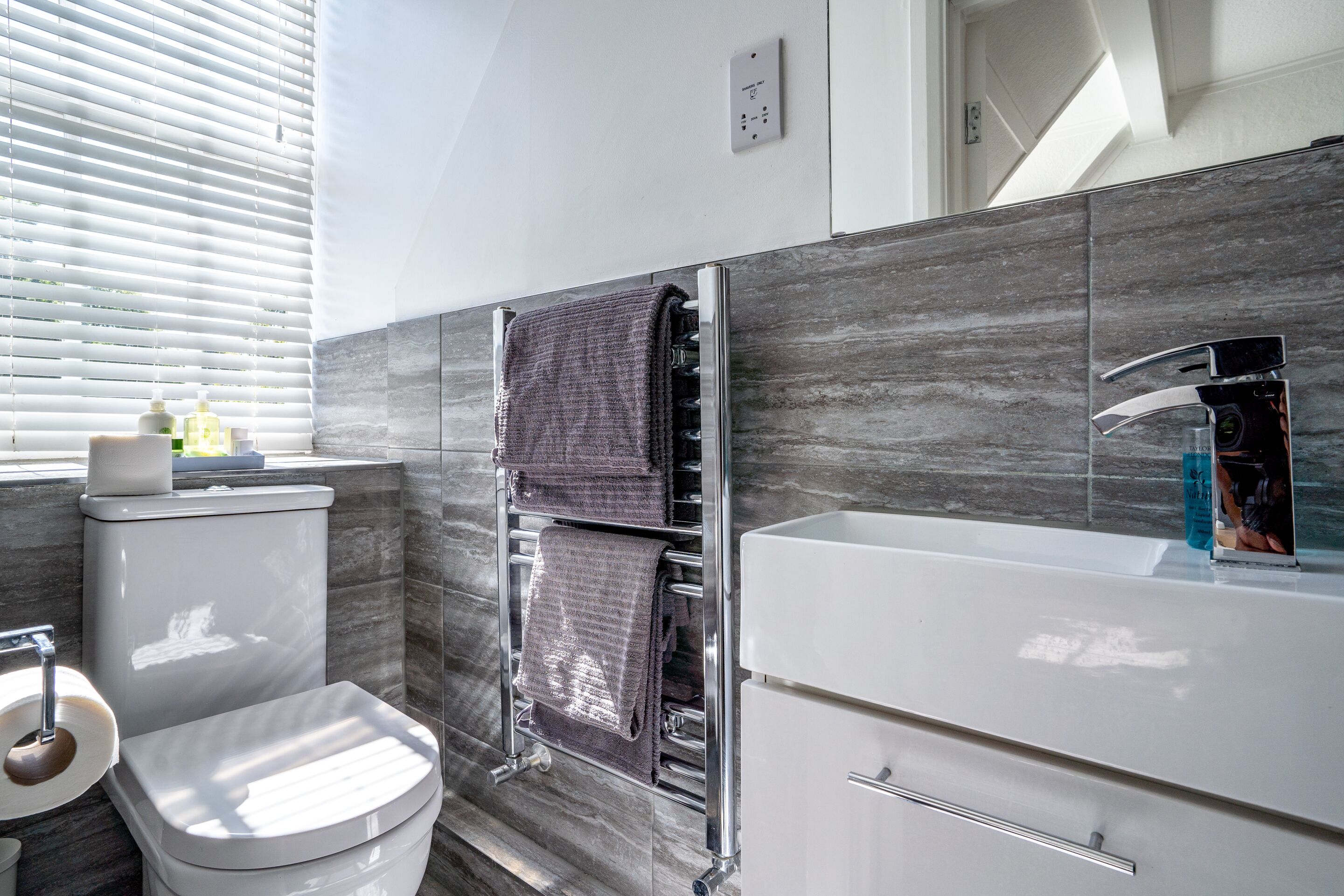 A modern bathroom with a toilet, sink, and towel rack.