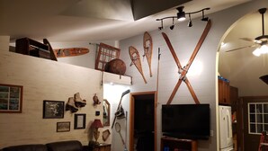 Un accogliente soggiorno con un divano in pelle, una televisione a schermo piatto, sci di legno e una libreria.