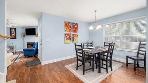A dining area with a wooden table and chairs, a fireplace, and artwork on the wall.