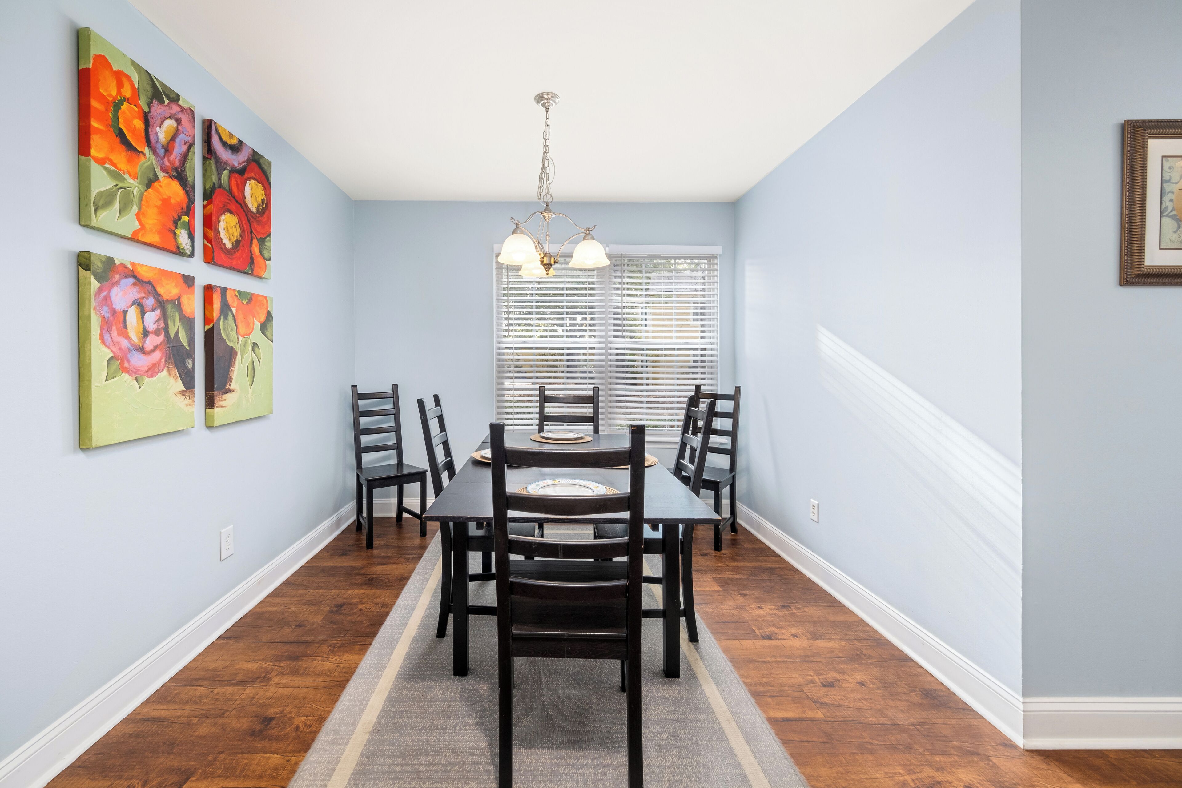 A dining area with a table and chairs, a chandelier, and artwork on the walls.