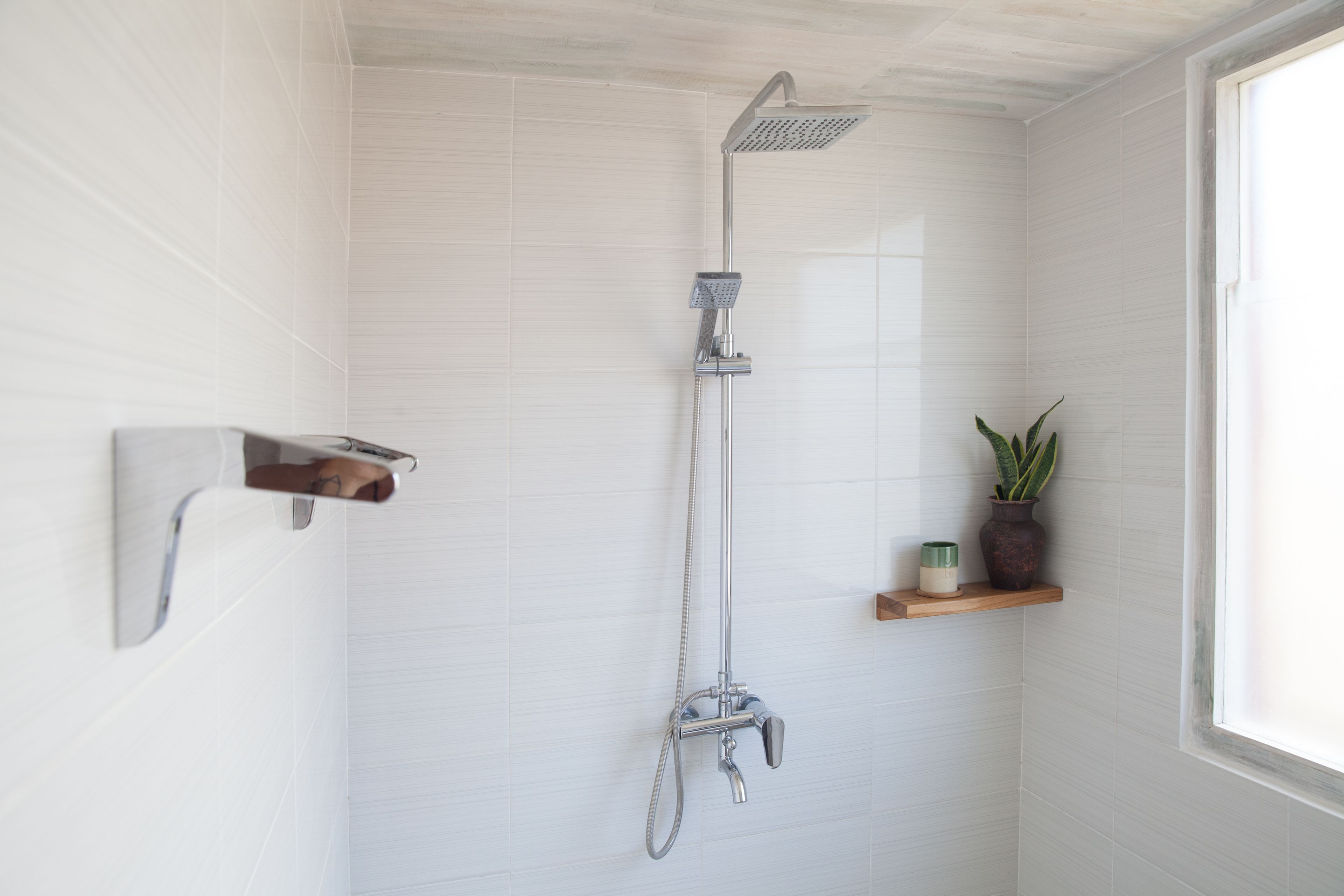 A shower with a handheld showerhead and a wall-mounted faucet.