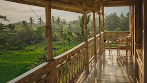 A wooden porch with a view of a lush green landscape and palm trees. - B Saya Villas Ubud (Ubud)