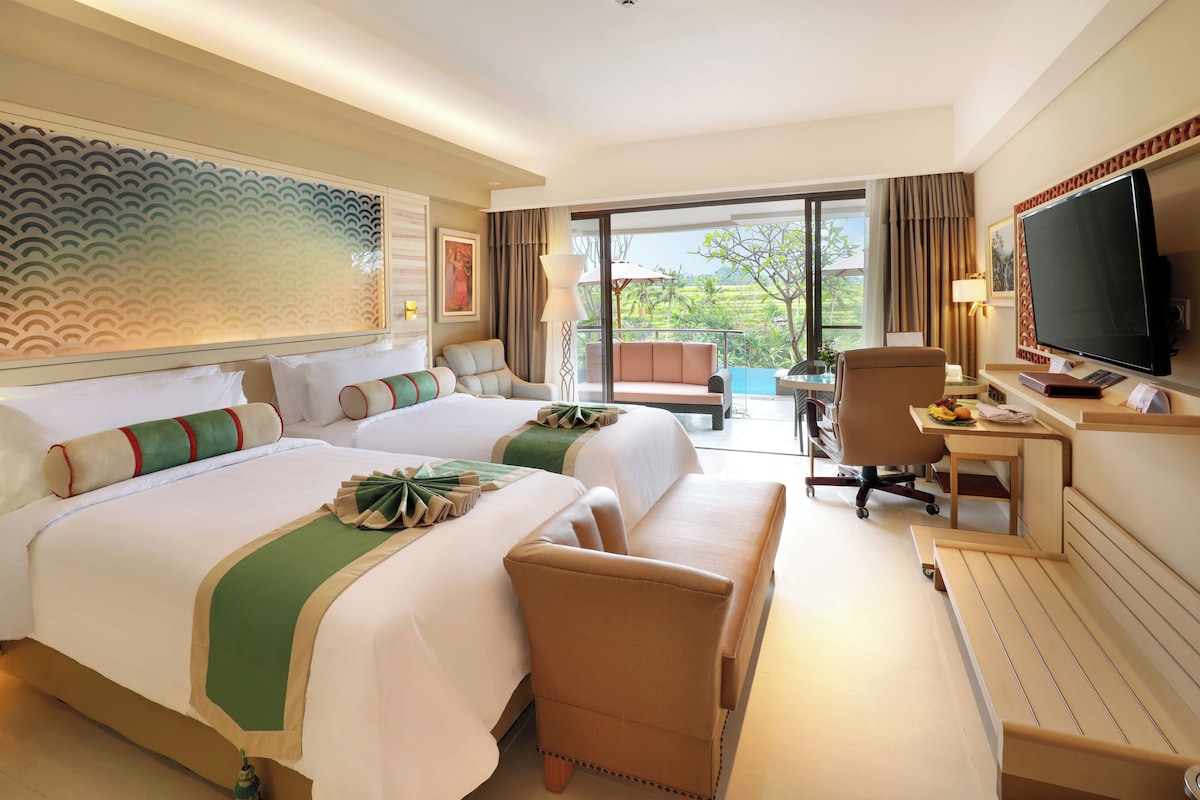 A hotel room with two beds, a desk, a chair, a TV, and a balcony with a view.