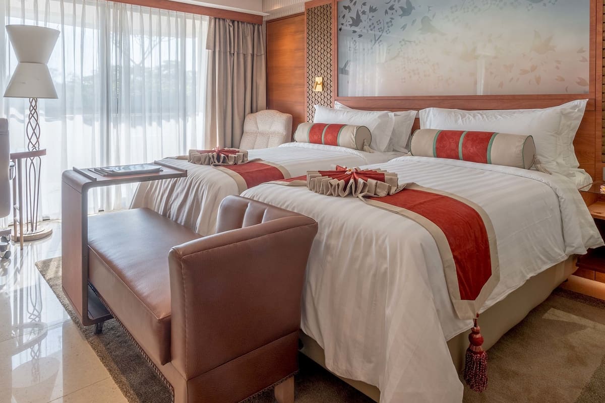 A hotel room with a large bed, a desk, a chair, and a window with curtains.