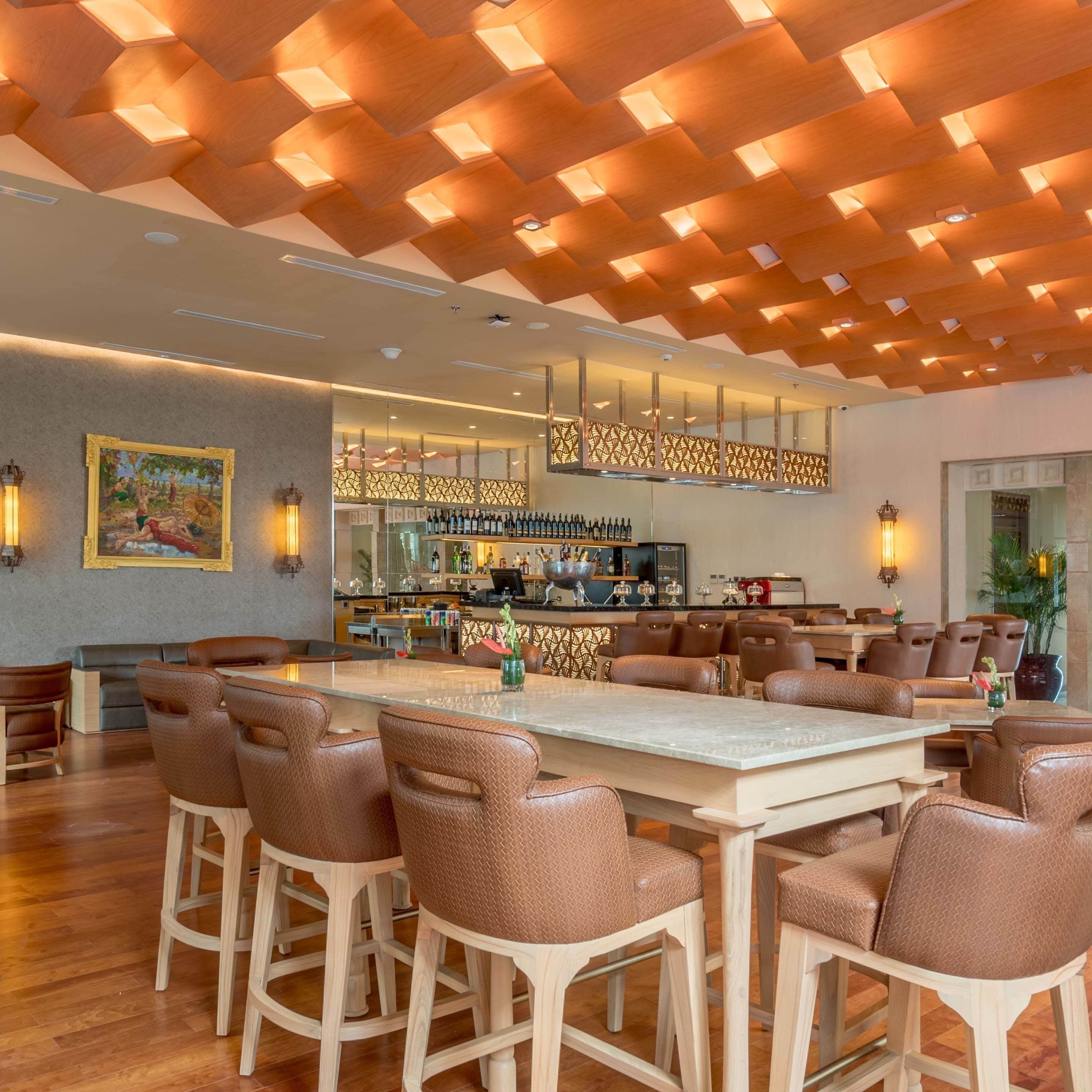 A modern bar area with a wooden ceiling, bar stools, and a bar counter.