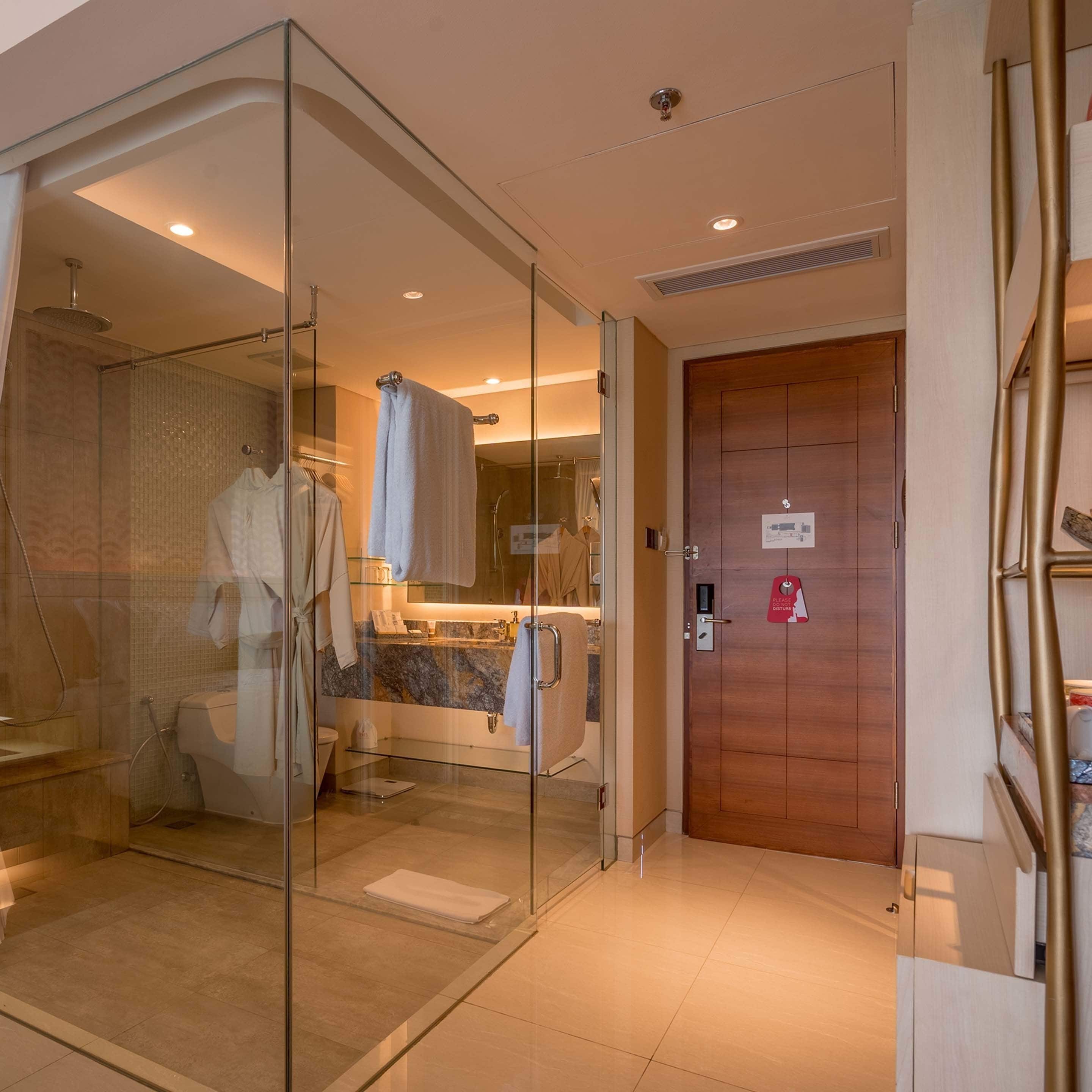 Un baño moderno con cabina de ducha de vidrio, puerta de madera y encimera de mármol.