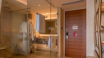 Un baño moderno con cabina de ducha de vidrio, puerta de madera y encimera de mármol.