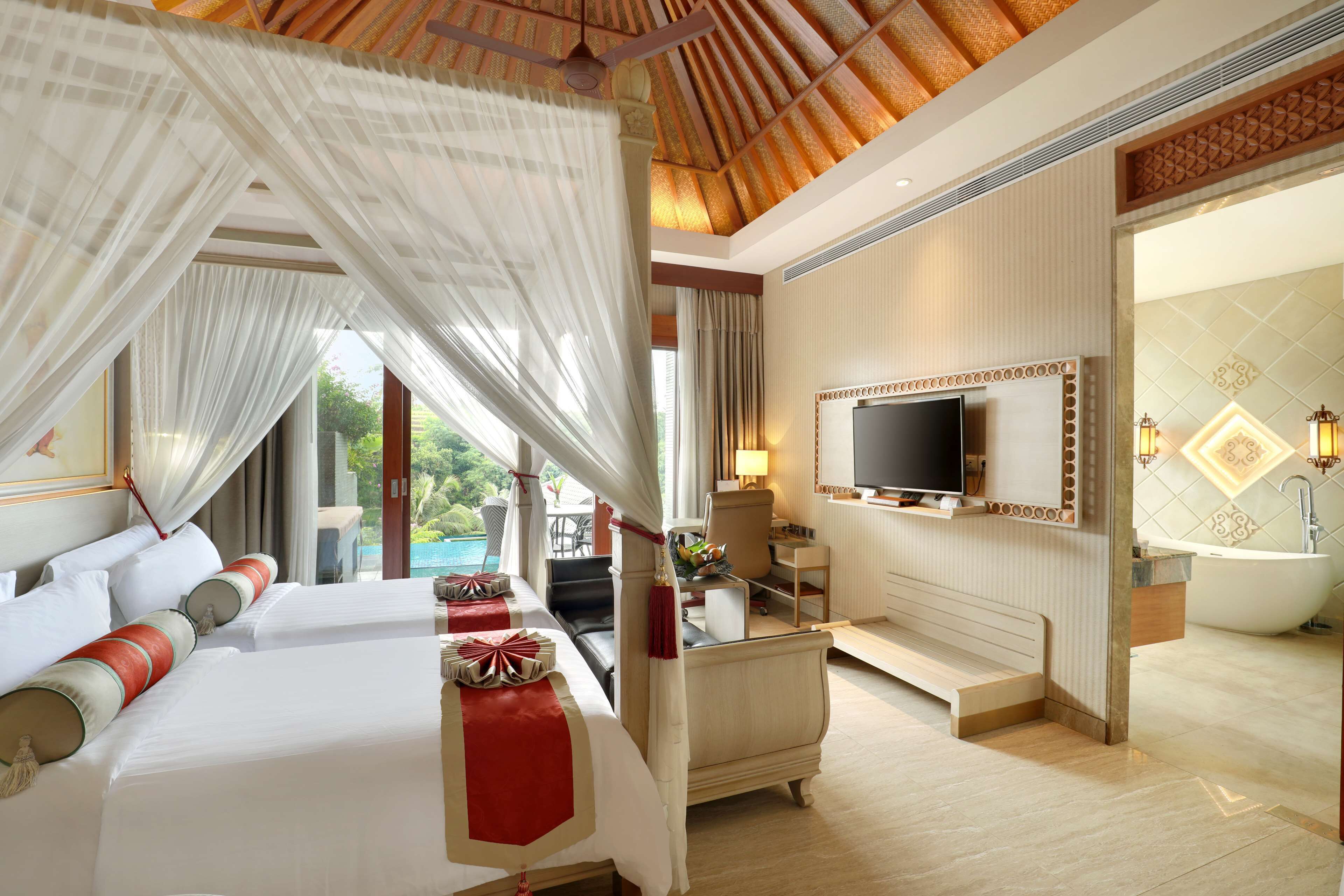 Une chambre d’hôtel luxueuse, dotée d’un grand lit, d’une télévision, d’un bureau et d’une baignoire.