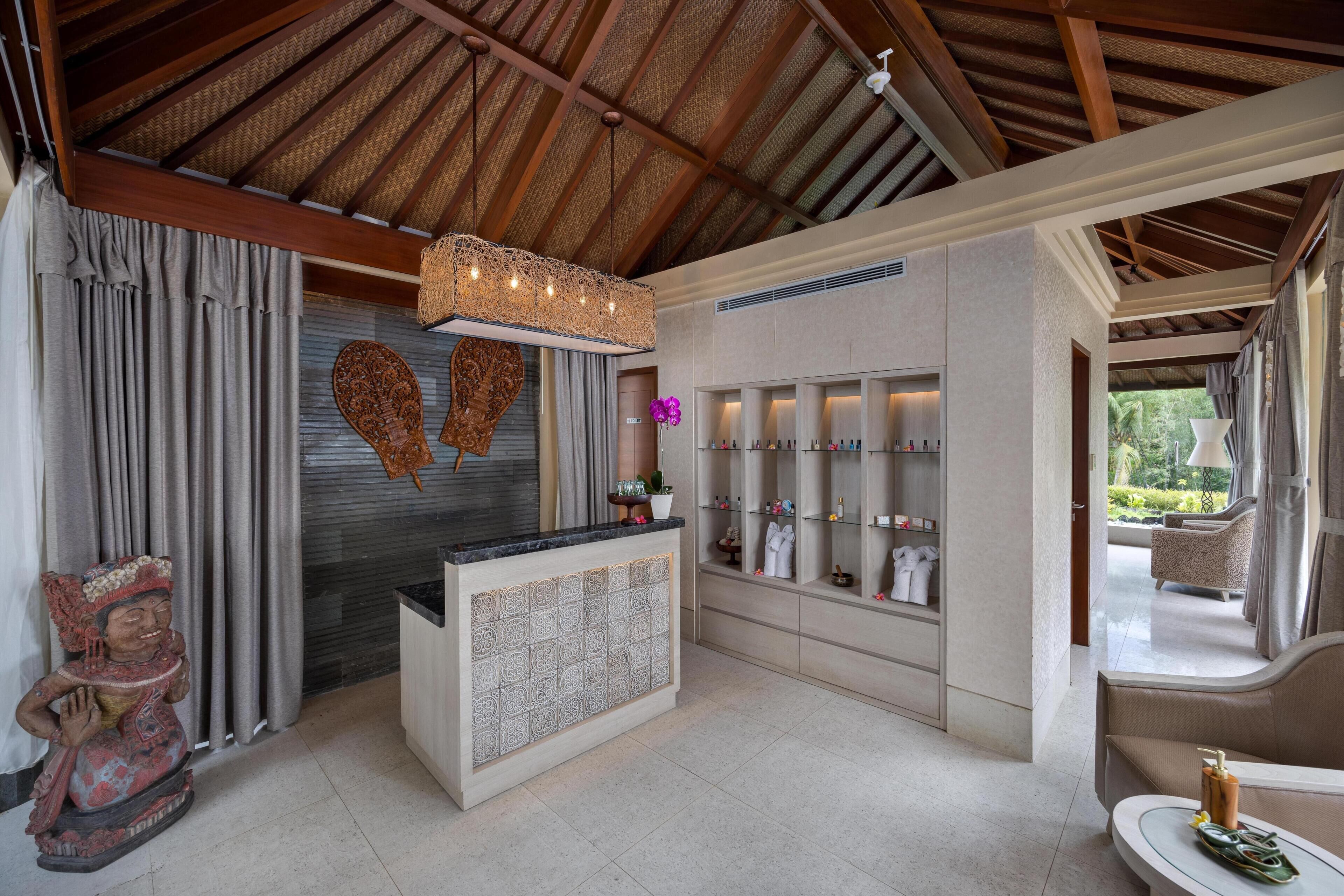 A reception area with a wooden ceiling, a reception desk, a wall-mounted shelf with toiletries, and a statue.