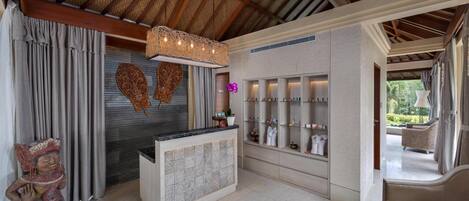 A reception area with a wooden ceiling, a reception desk, a wall-mounted shelf with toiletries, and a statue.
