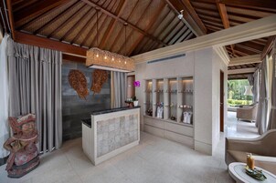 A reception area with a wooden ceiling, a reception desk, a wall-mounted shelf with toiletries, and a statue.