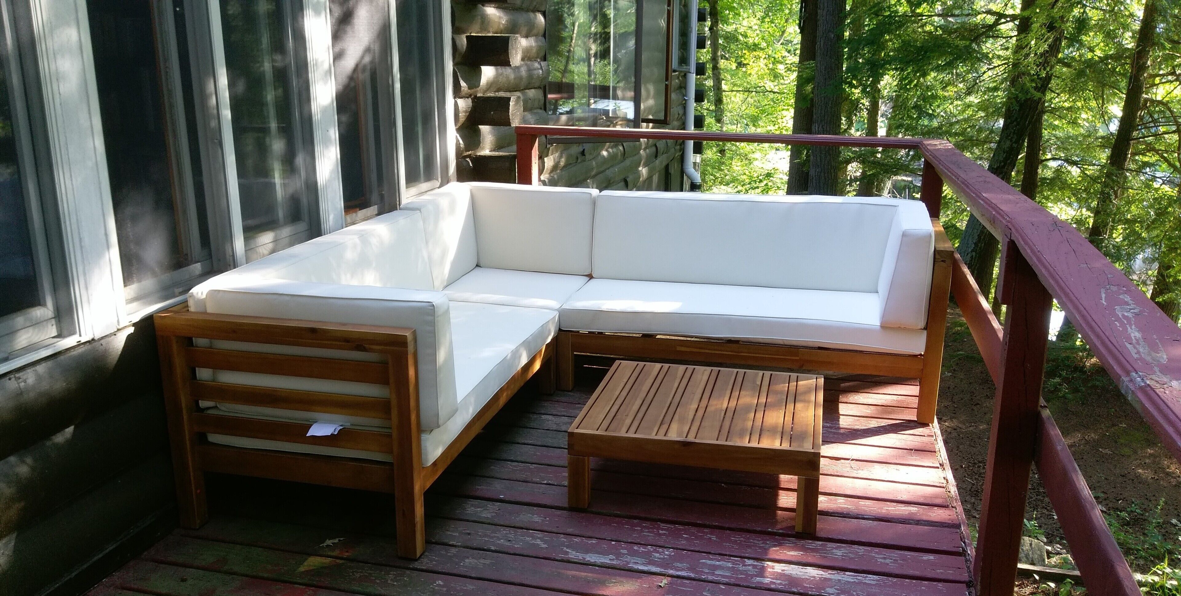 A wooden deck with a white sofa, a wooden bench, and a small table.