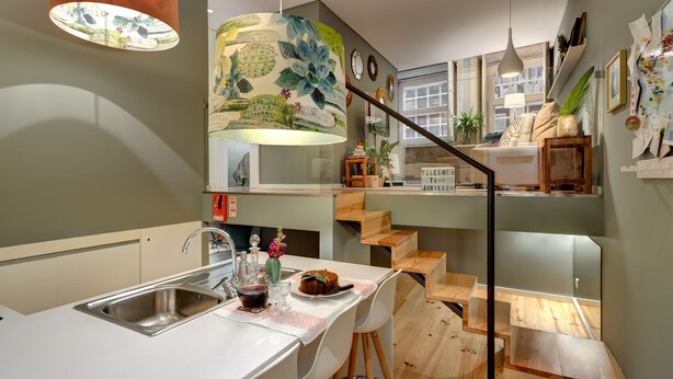 Een moderne keuken met een centraal eiland, een inbouwspoelbak en een trap naar een vide.