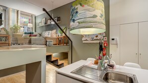 Een moderne keuken met een roestvrijstalen spoelbak, een houten eettafel en een grote decoratieve lamp.