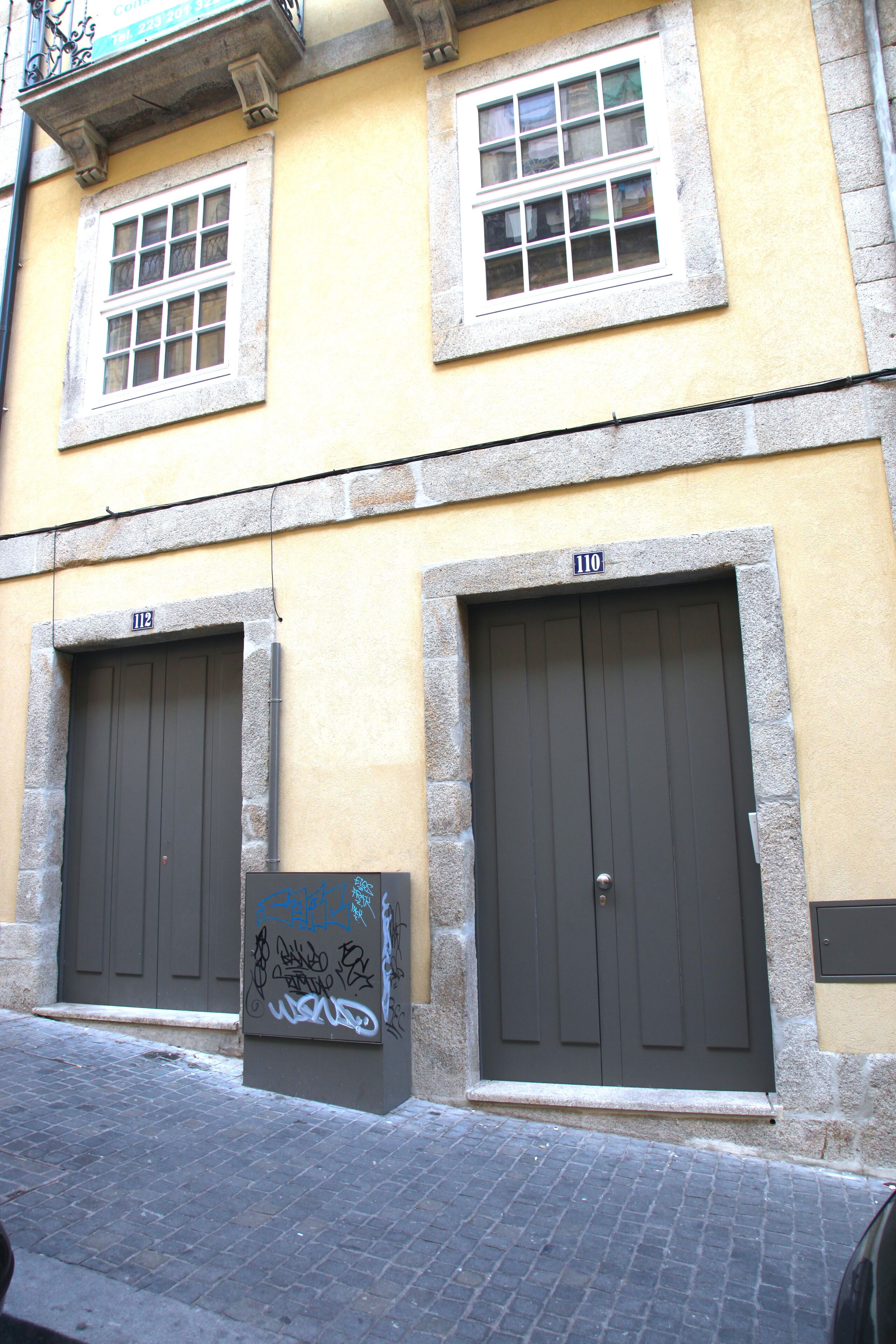 Un edificio con dos puertas grandes y dos ventanas; cada puerta tiene un número encima.