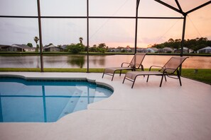 Piscina con sillas de descanso y vista a casas al otro lado del agua.