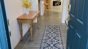 A hallway with a wooden table and chairs, a patterned rug, and a blue door. - EAGLE POINTE SOUTH ON THE LARGER LAKE  A NEW VACATION/HOLIDAY EXPERIENCE (Kissimmee)