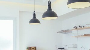 Una cocina moderna con encimera de mármol, sillas de madera e iluminación colgante.
