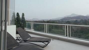 A balcony with two lounge chairs and a glass door leading to an interior space.