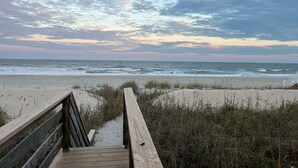 A wooden boardwalk leading to a beach with a cloudy sky.