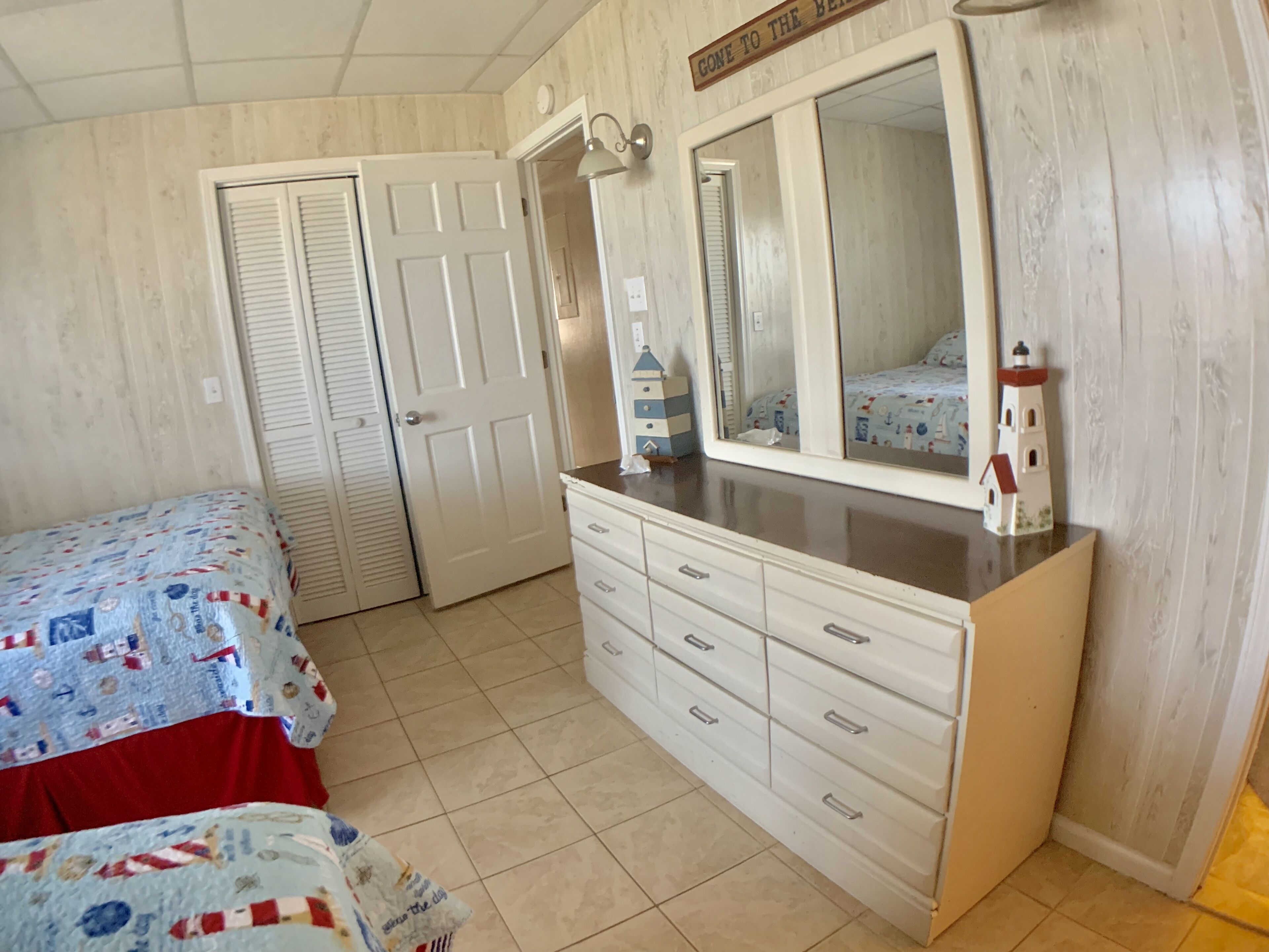 A bedroom with two beds, a dresser, a mirror, and a door.