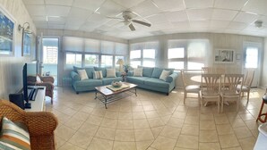 A spacious living room with a large sofa, a coffee table, and a dining area with chairs.
