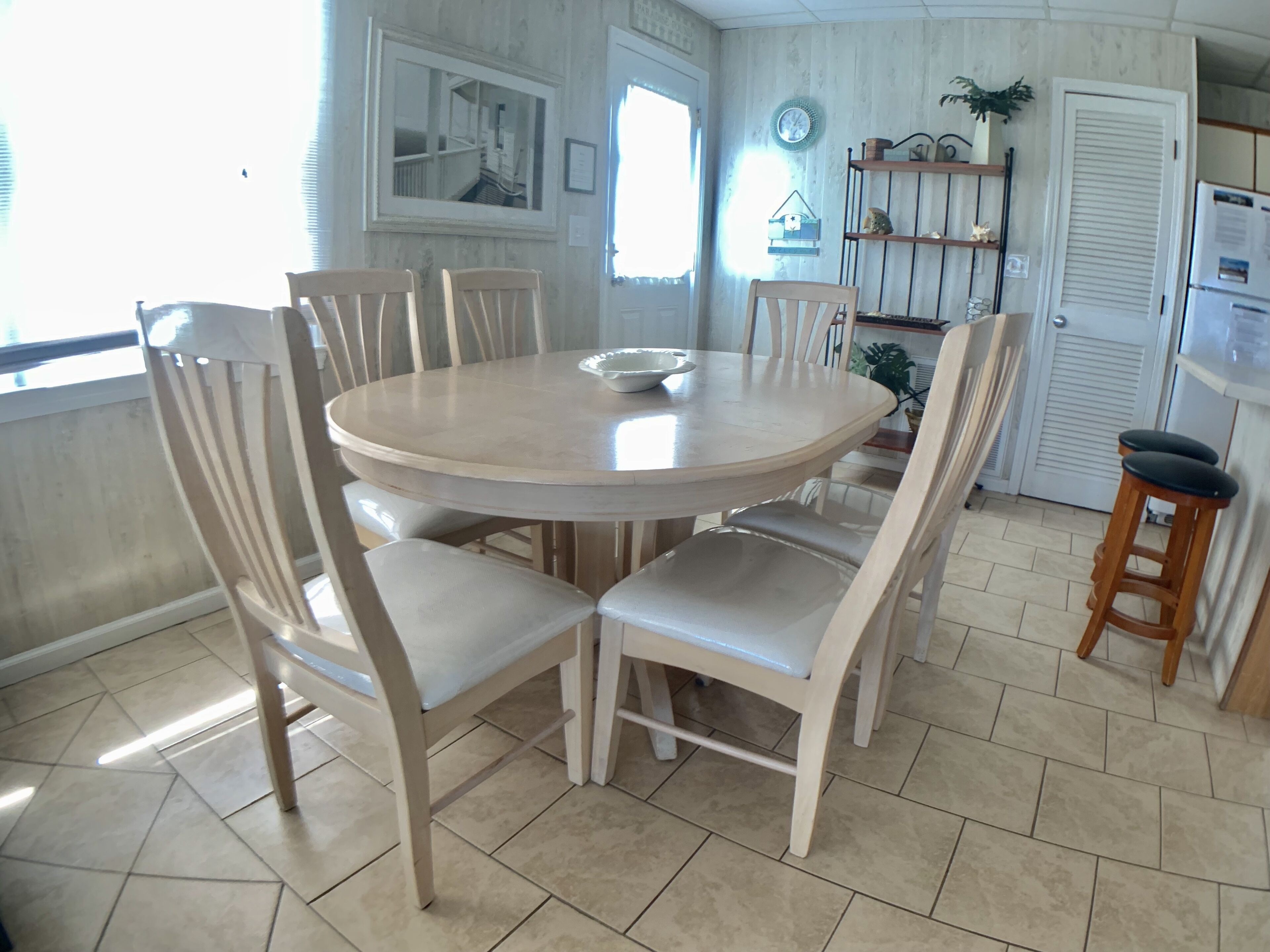 A dining area with a round table, six chairs, and a small stool.