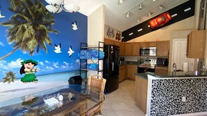 Uma cozinha moderna com uma ilha central, armários de madeira e uma geladeira preta.