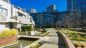 Uma área residencial moderna com calçada pavimentada, elementos aquáticos e vegetação.