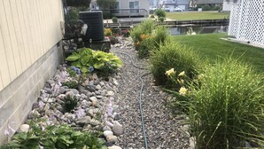 A garden with a gravel path, various plants, and a water feature. - Private Canalfront House, Dock, Deck, Fire Pit, Parking, 7th house to the Beach (South Bethany Beach)
