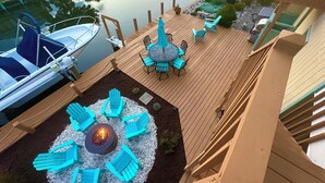 A deck with outdoor seating and a fire pit, overlooking a calm body of water with boats. - Private Canalfront House, Dock, Deck, Fire Pit, Parking, 7th house to the Beach (South Bethany Beach)