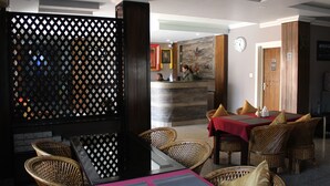 A hotel lobby with wicker furniture, a reception desk, and a clock on the wall. - Hotel Butsugen (Kathmandu)