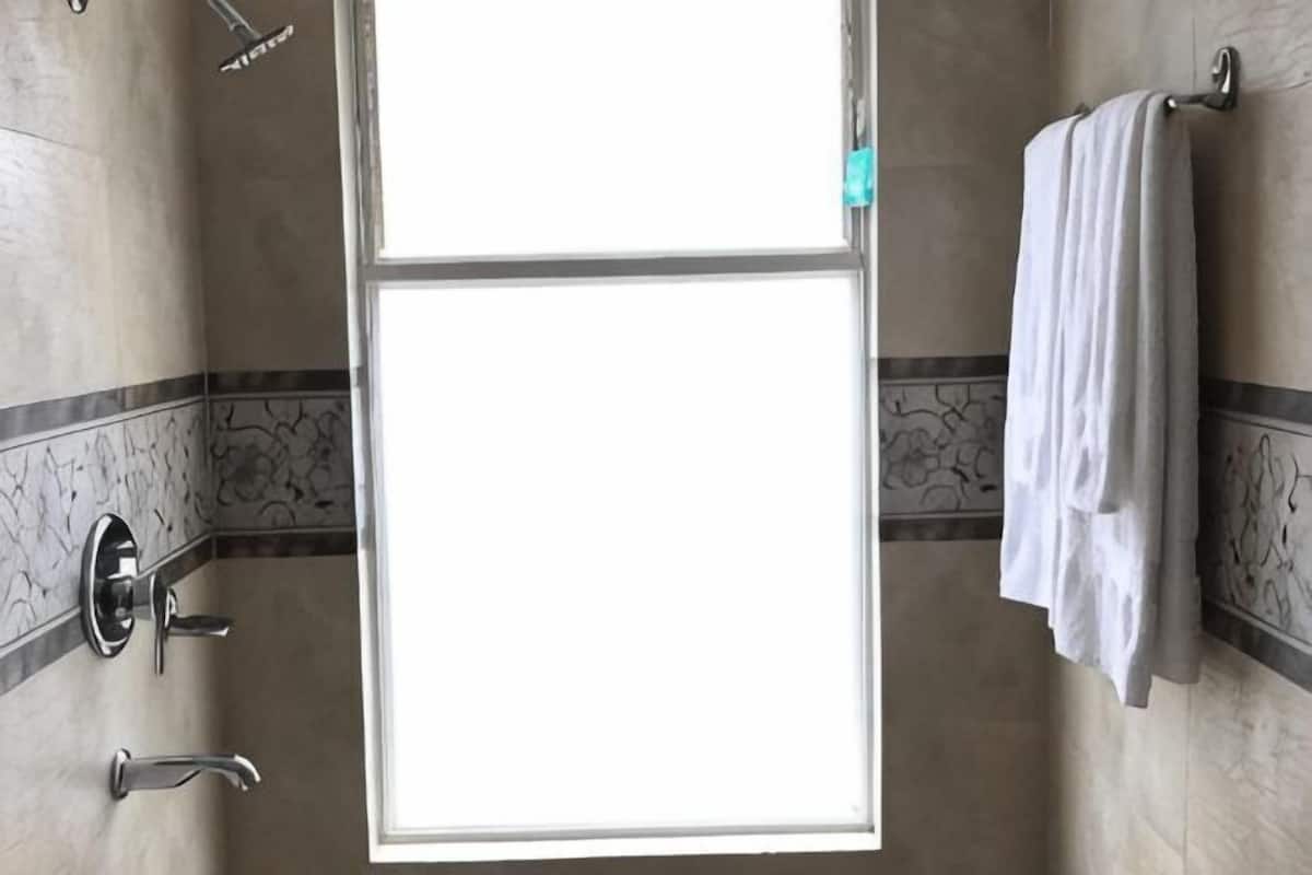 Ein Badezimmer mit Dusche, Handtuchhalter und einem Fenster.