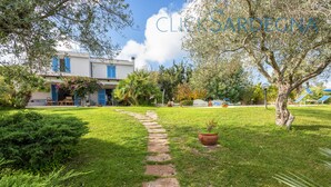 A pathway leading to a house with a garden, a blue sky, and a sign reading "CLICCARDECONA". - Spectacular Villa with independent pool for 8 people near the beach (Alghero Italy)
