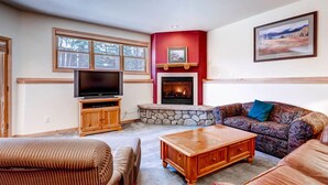 Una sala de estar con chimenea, televisor y sofá.