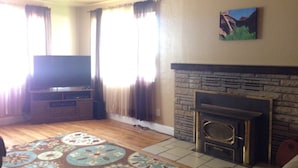 A living room with a television, fireplace, and patterned rug. - Center of Kanab! Inviting, clean & spacious (Kanab)