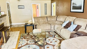 A living room with a sectional sofa, a glass coffee table, and patterned carpet. - Center of Kanab! Inviting, clean & spacious (Kanab)