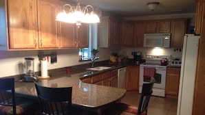 A kitchen with wooden cabinets, a granite countertop, a built-in microwave, a stove, and a sink. - Center of Kanab! Inviting, clean & spacious (Kanab)