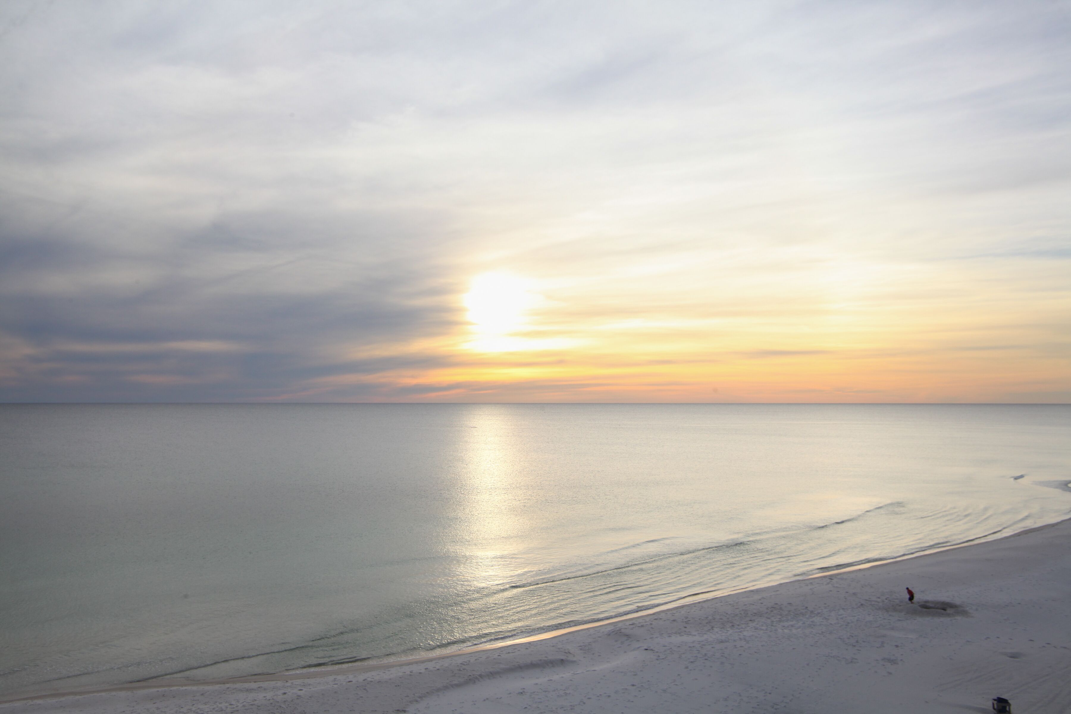 A beach with a calm sea and a sunset.