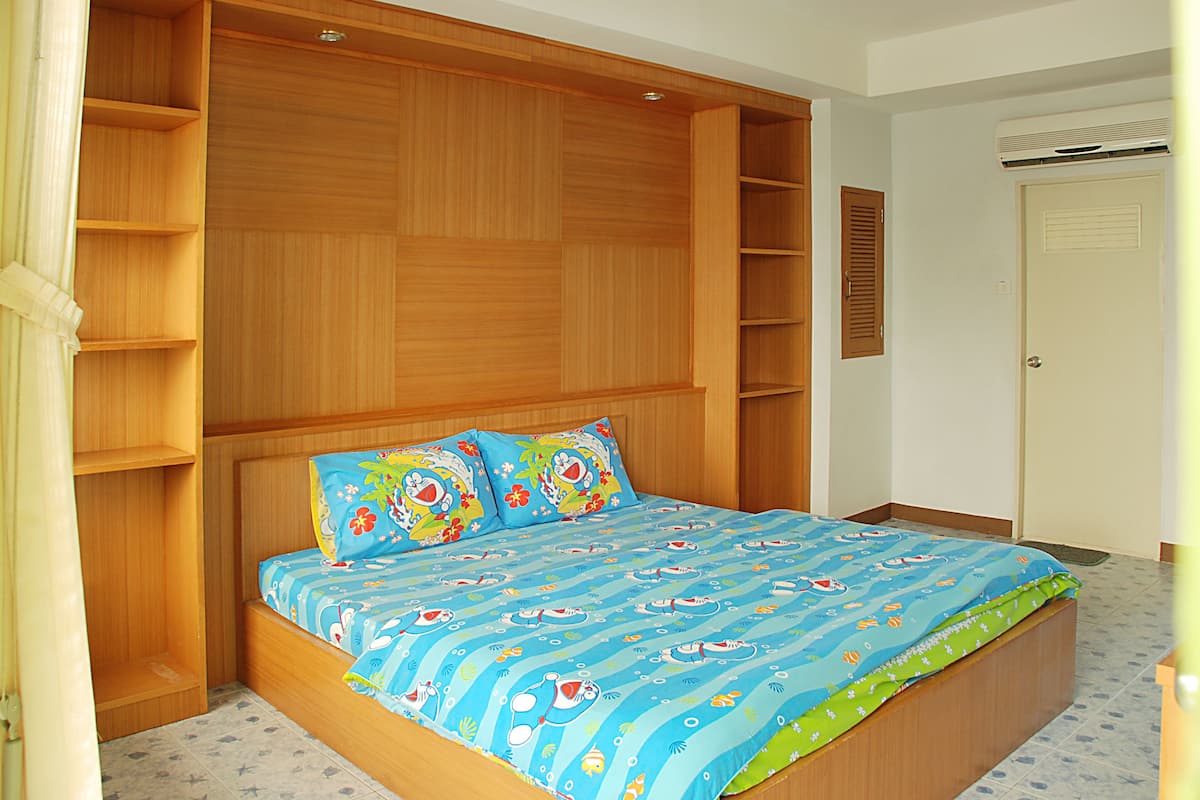 Una camera da letto con un letto grande, scaffali a muro e una porta con una feritoia.